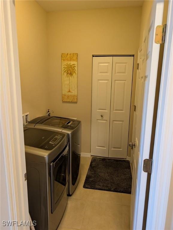 laundry room with light tile patterned floors, separate washer and dryer, and laundry area