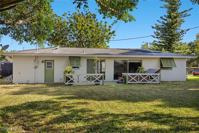 rear view of property featuring stucco siding and a yard