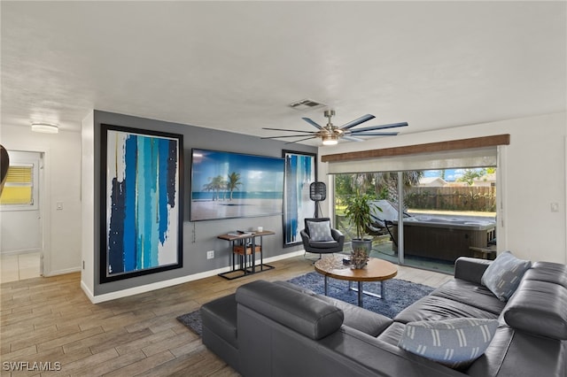 living area with visible vents, a ceiling fan, baseboards, and wood finished floors