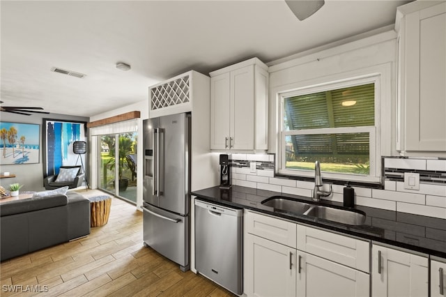 kitchen with a sink, stainless steel appliances, open floor plan, backsplash, and visible vents