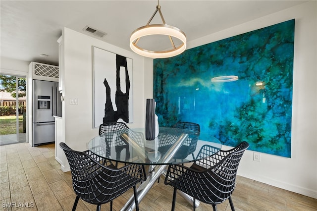 dining room featuring visible vents, an accent wall, baseboards, and wood finished floors