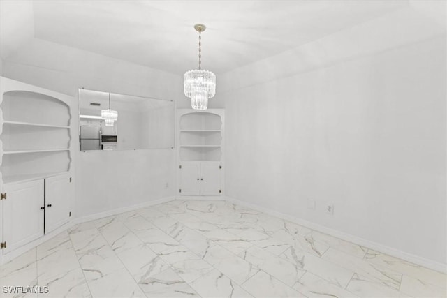 empty room with marble finish floor, an inviting chandelier, and baseboards