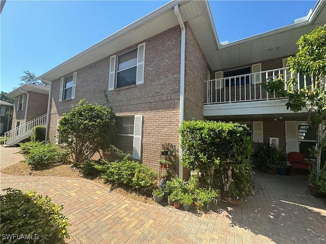 view of side of home with a balcony and brick siding