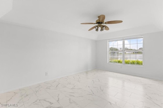 spare room featuring marble finish floor, ceiling fan, a tray ceiling, and baseboards