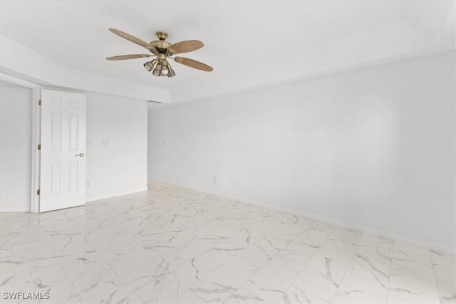 empty room featuring a ceiling fan, marble finish floor, and baseboards