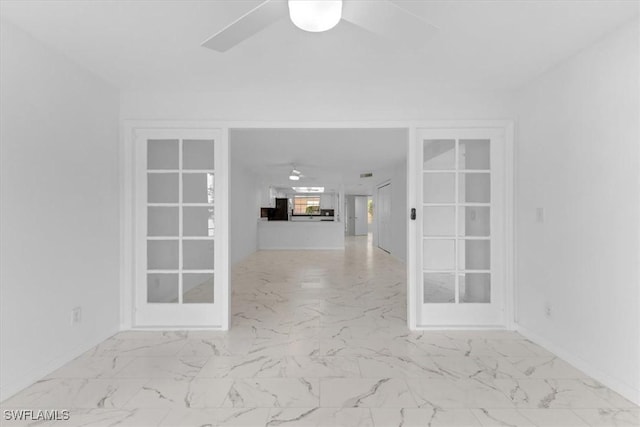 spare room with a ceiling fan, marble finish floor, and baseboards