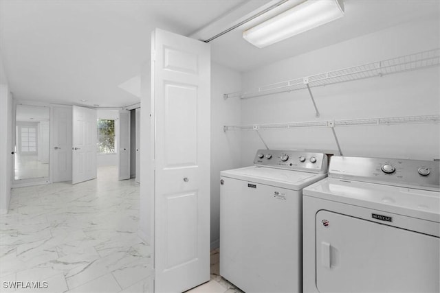 washroom featuring separate washer and dryer, marble finish floor, and laundry area