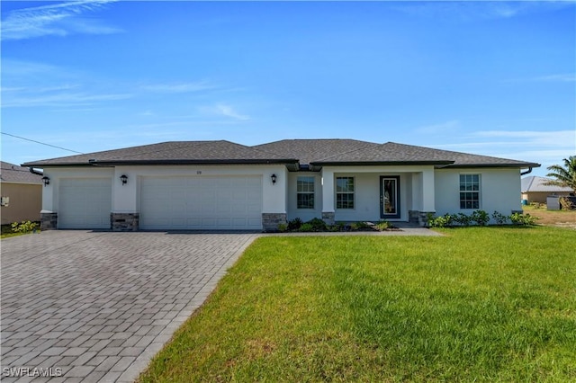 prairie-style home with stucco siding, driveway, a front yard, and a garage