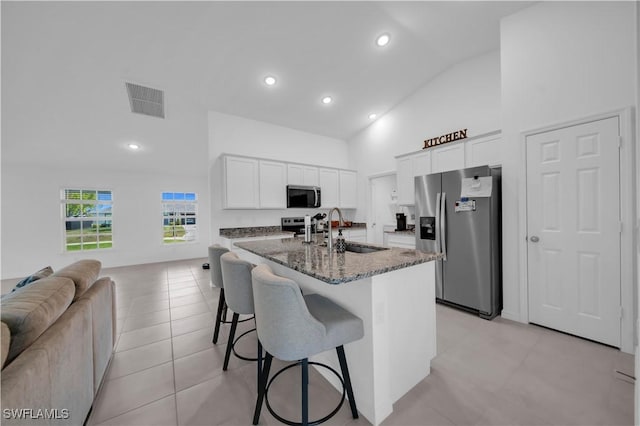kitchen featuring stainless steel appliances, a sink, visible vents, open floor plan, and high vaulted ceiling