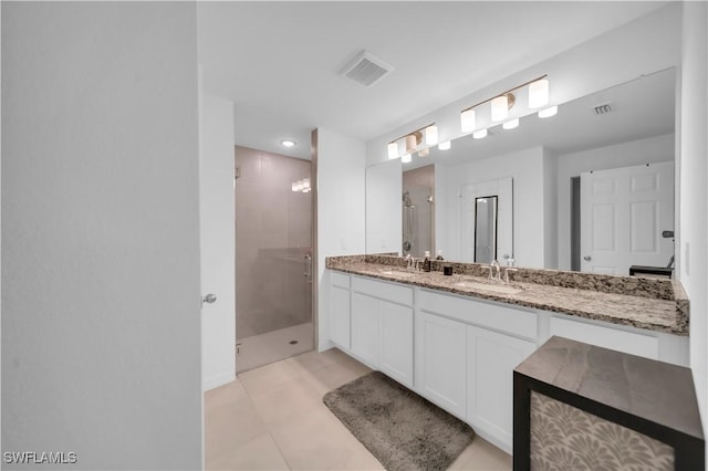 bathroom with a stall shower, double vanity, a sink, and visible vents