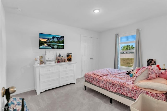 bedroom featuring a closet, light colored carpet, and baseboards