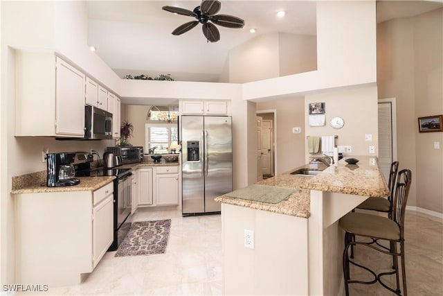 9895 El Greco Cir, Bonita Springs, FL 34135 - kitchen with stainless steel appliances, a sink, a kitchen bar, light stone counters, and ceiling fan