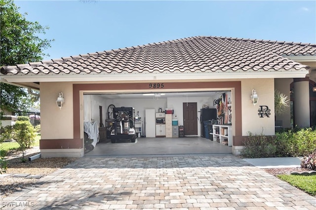 9895 El Greco Cir, Bonita Springs, FL 34135 - doorway to property with decorative driveway, stucco siding, a tiled roof, and an attached garage