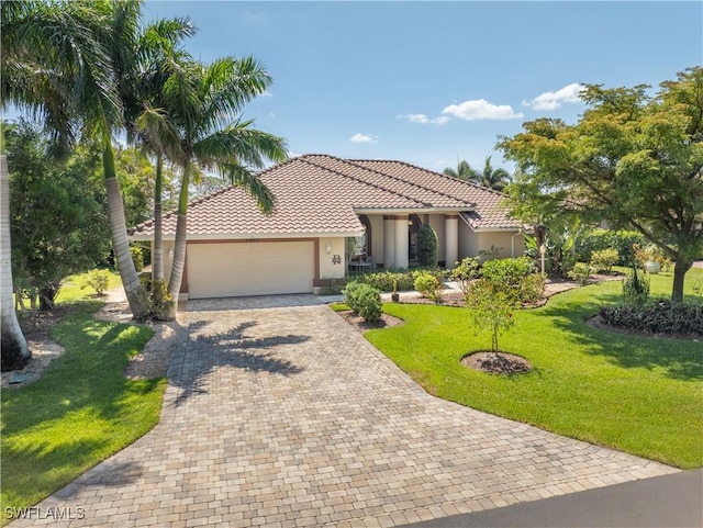 9895 El Greco Cir, Bonita Springs, FL 34135 - mediterranean / spanish house with stucco siding, an attached garage, a tile roof, a front lawn, and decorative driveway