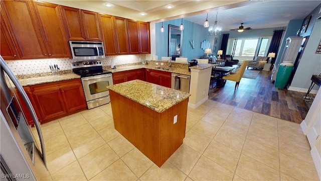 kitchen featuring a sink, light tile patterned floors, a peninsula, open floor plan, and stainless steel appliances