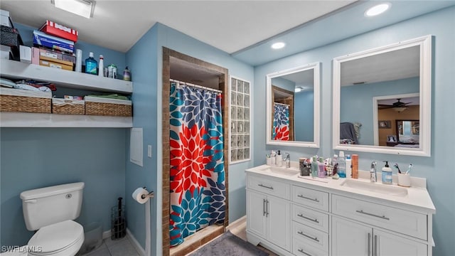 full bath featuring toilet, double vanity, ceiling fan, and a sink