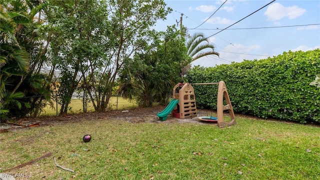 view of playground with a lawn and fence