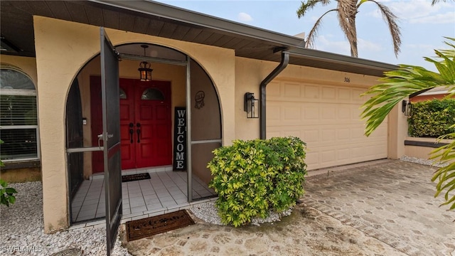 property entrance with a garage, driveway, and stucco siding