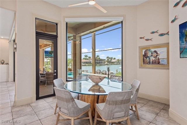 dining room with a water view, baseboards, light tile patterned floors, and ceiling fan