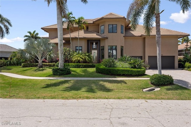 view of front facade featuring driveway, a front lawn, a tile roof, and stucco siding