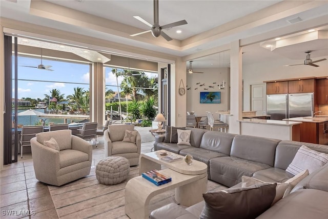 living area featuring a ceiling fan, recessed lighting, a wealth of natural light, and a raised ceiling