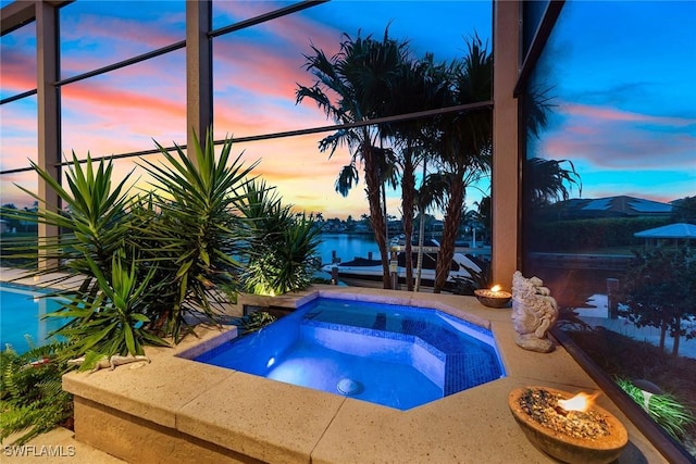 pool at dusk featuring an in ground hot tub