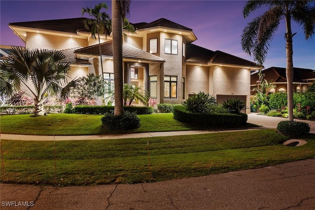 view of front of house with a lawn, a garage, driveway, and stucco siding