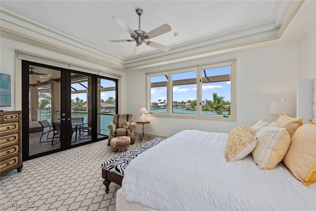 carpeted bedroom featuring french doors, a raised ceiling, a water view, and access to exterior
