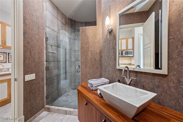 full bath with a sink, a stall shower, and tile patterned floors