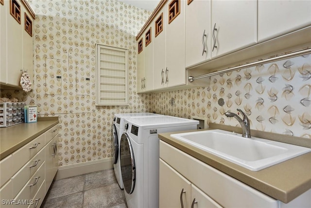 laundry room with a sink, cabinet space, washer and dryer, and wallpapered walls