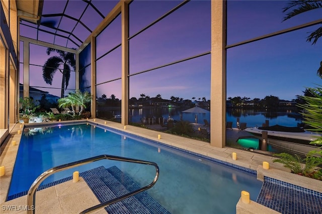 outdoor pool featuring glass enclosure, a patio, and a water view