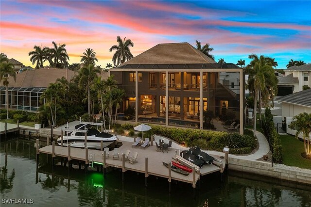 130 Hollyhock Ct, Marco Island, FL 34145 - back of property at dusk featuring a balcony, a water view, a patio, and fence