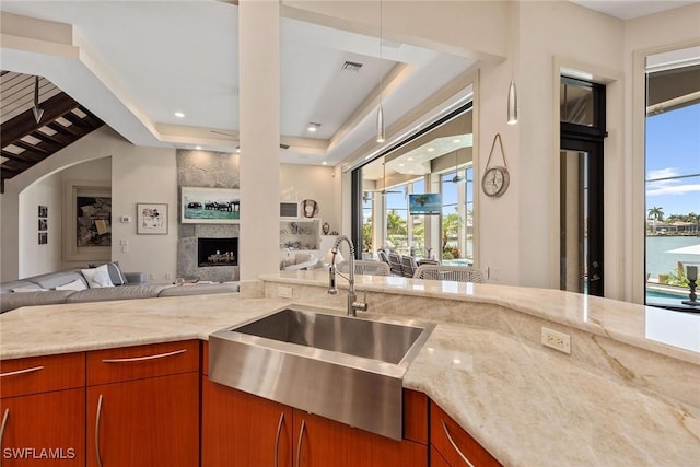 130 Hollyhock Ct, Marco Island, FL 34145 - kitchen with open floor plan, a sink, light stone counters, a premium fireplace, and brown cabinets