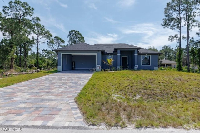 prairie-style house featuring an attached garage, decorative driveway, stucco siding, and a front yard