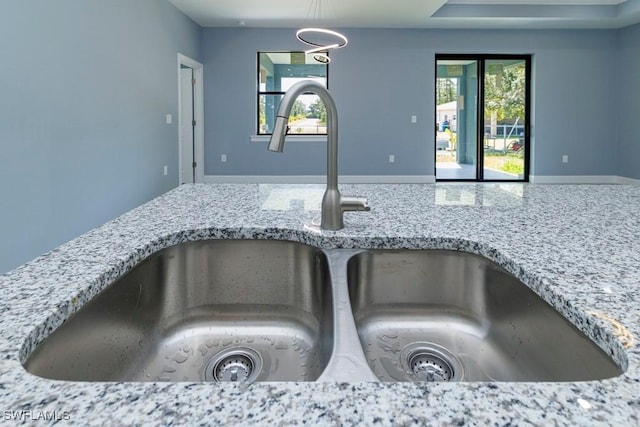 room details with a sink, pendant lighting, and light stone countertops