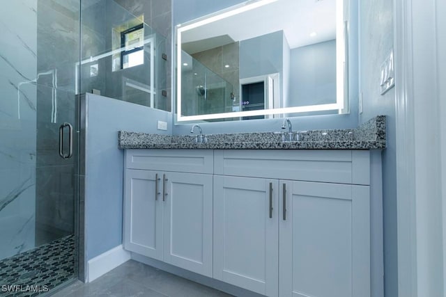 bathroom featuring double vanity, a sink, baseboards, and a shower stall