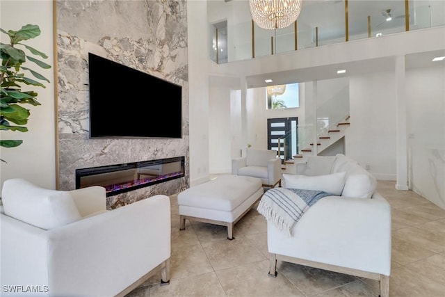 9680 Pineapple Preserve Ct, Fort Myers, FL 33908 - tiled living room featuring a towering ceiling, a fireplace, stairway, baseboards, and an inviting chandelier