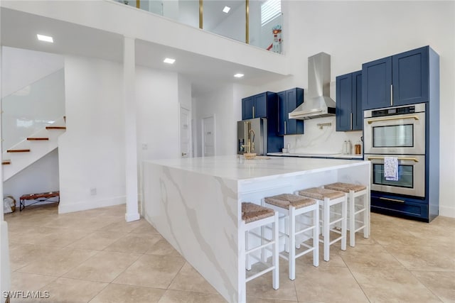 9680 Pineapple Preserve Ct, Fort Myers, FL 33908 - kitchen with light tile patterned floors, appliances with stainless steel finishes, wall chimney exhaust hood, and a towering ceiling