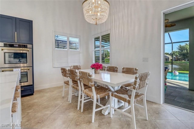 9680 Pineapple Preserve Ct, Fort Myers, FL 33908 - dining room with baseboards, a towering ceiling, light tile patterned floors, and a chandelier
