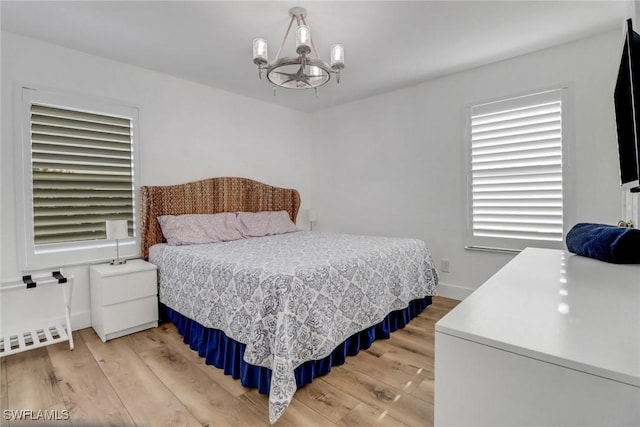 9680 Pineapple Preserve Ct, Fort Myers, FL 33908 - bedroom with baseboards, light wood-style flooring, and a notable chandelier