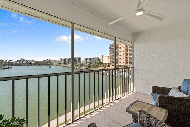 balcony featuring a ceiling fan, a water view, and a view of city