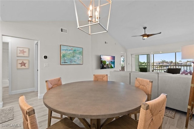 dining room with light wood-type flooring, high vaulted ceiling, baseboards, a chandelier, and a ceiling fan