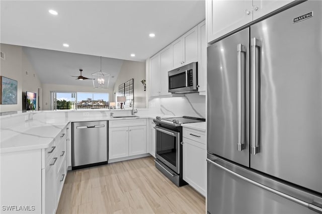 kitchen with appliances with stainless steel finishes, white cabinets, recessed lighting, light stone counters, and a sink