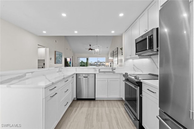 kitchen with appliances with stainless steel finishes, a sink, recessed lighting, white cabinetry, and light stone counters