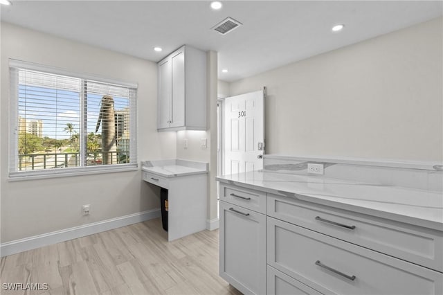 kitchen featuring recessed lighting, baseboards, light stone counters, and light wood-type flooring