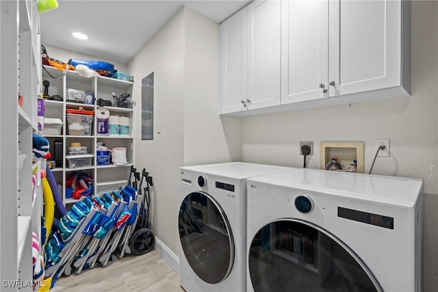 clothes washing area featuring cabinet space, washing machine and dryer, wood finished floors, and baseboards