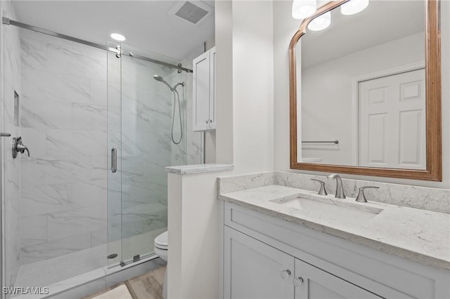full bath featuring toilet, a marble finish shower, and vanity