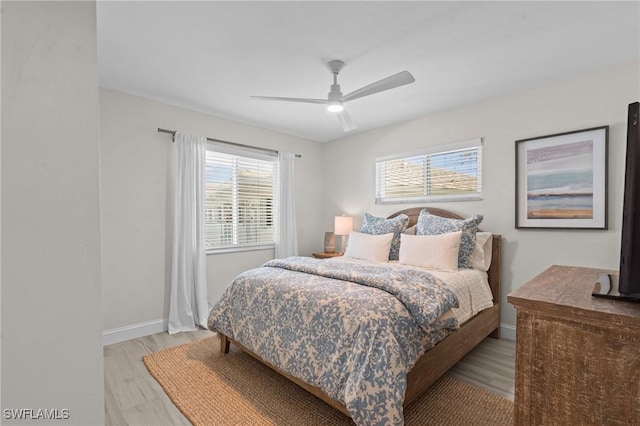 bedroom with multiple windows, light wood finished floors, baseboards, and ceiling fan