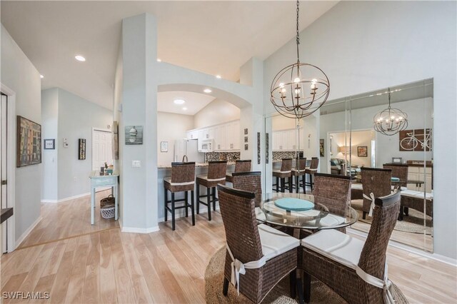 6171 Mandalay Cir Unit 28, Naples, FL 34112 - dining area with arched walkways, high vaulted ceiling, a notable chandelier, and light wood-style floors