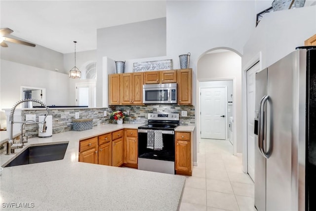 360 3rd St SW, Naples, FL 34117 - kitchen with stainless steel appliances, a sink, decorative backsplash, a ceiling fan, and a towering ceiling